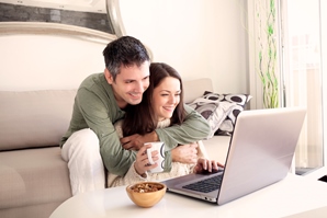 Junges lächelndes Paar in Umarmung vor dem Laptop