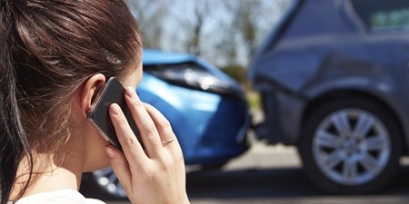 Frau telefoniert nach einem Autounfall